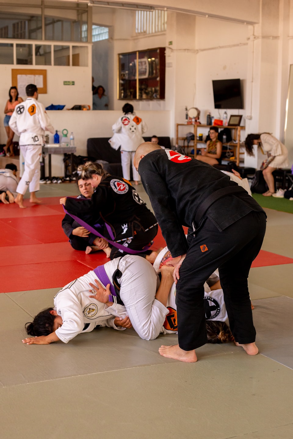 Studenten üben brasilianische Jiu-Jitsu-Techniken auf einer Gymnastikmatte.